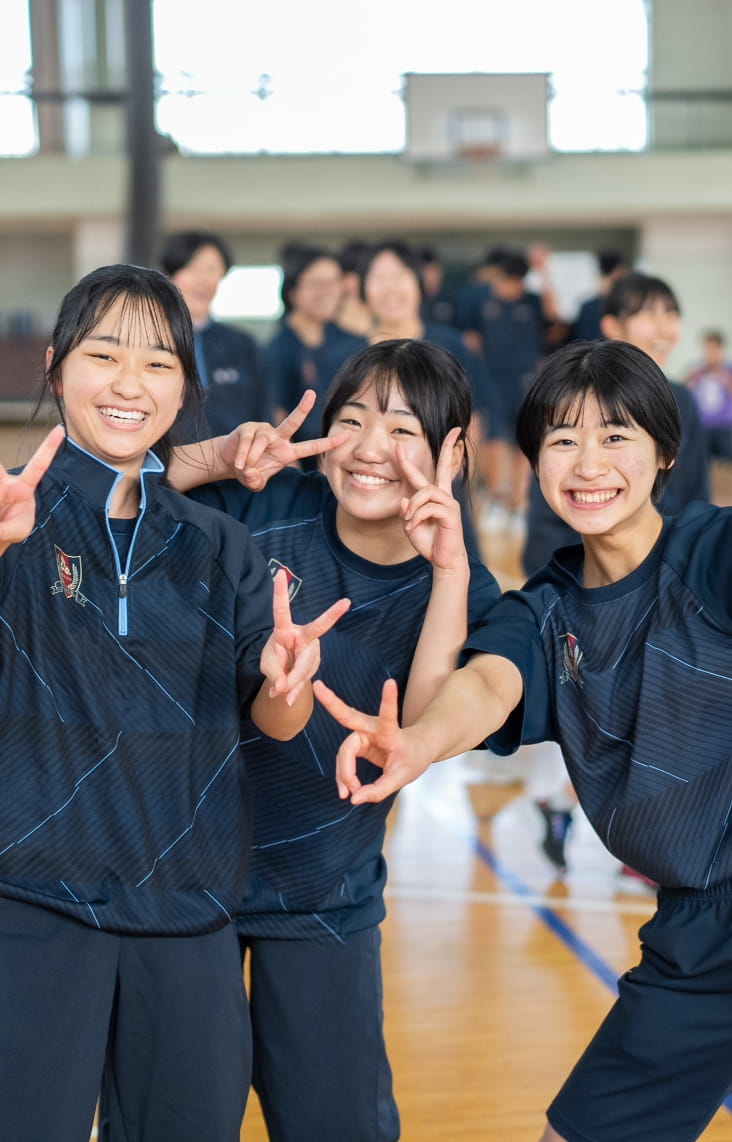 体操服を着た女子生徒たちがカメラに向かって笑顔でピースをしている
